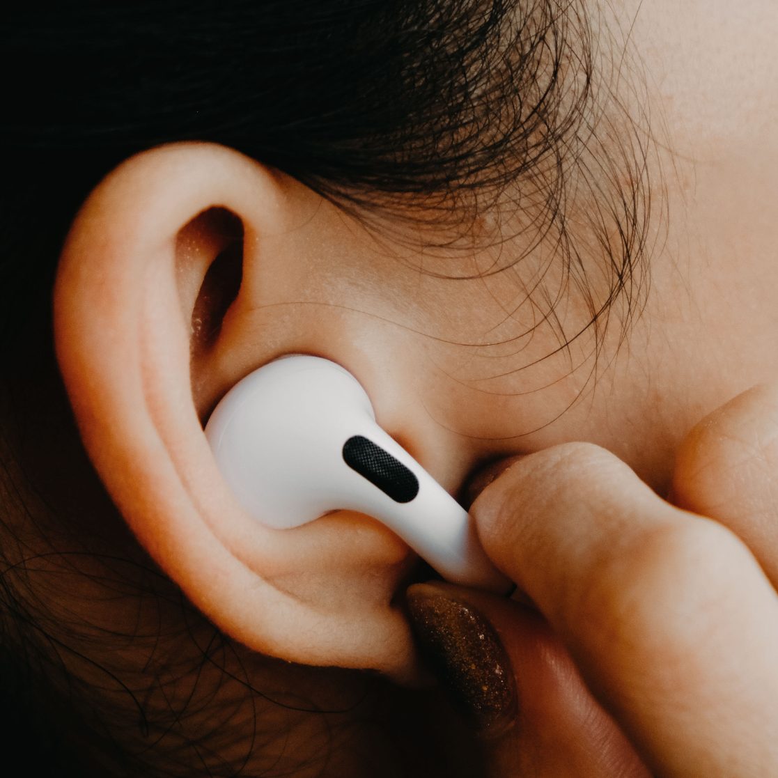 A picture of a lady holding an airpod to her ear,